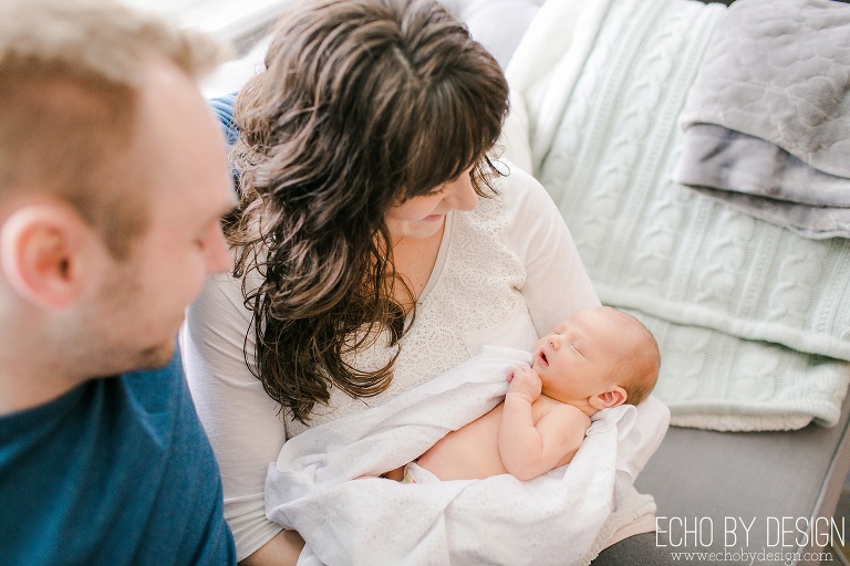 Mom holds newborn son as dad looks on