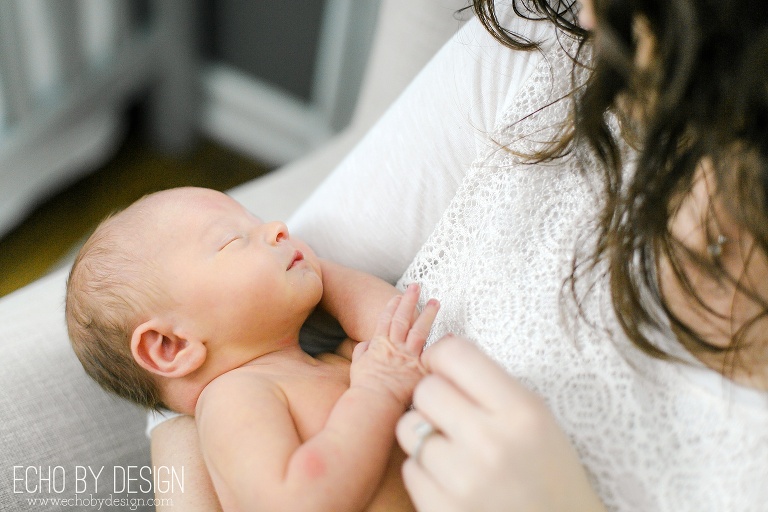 Mom plays with newborn sons fingers in rocking chair