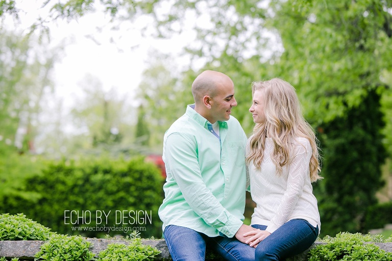 Couple holds hands on stone wall at Wegerzyn Gardens